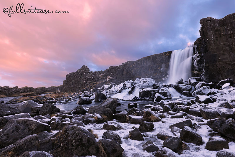 Winter waterfall against dramatic sky in Thingvellir National Park in Iceland