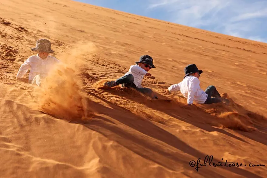 Children gliding down the sand dunes in Namibia
