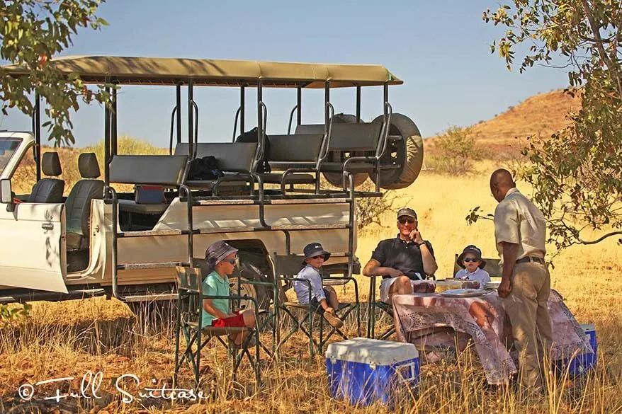 Family with kids having picnic lunch on safari in Africa