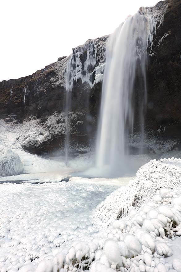 Partially frozen Seljalandsfoss waterfall in Iceland in winter