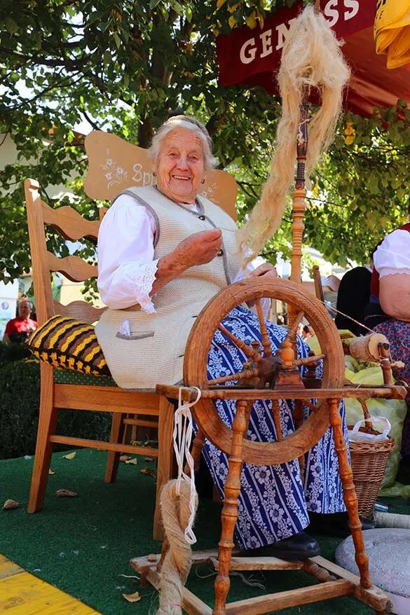 Las mujeres locales demostrando artesanías tradicionales en el mercado de agricultores en Tirol Austria