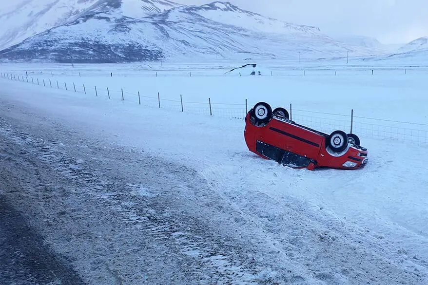 Car accident in Iceland in winter - red car upside down next to an icy road