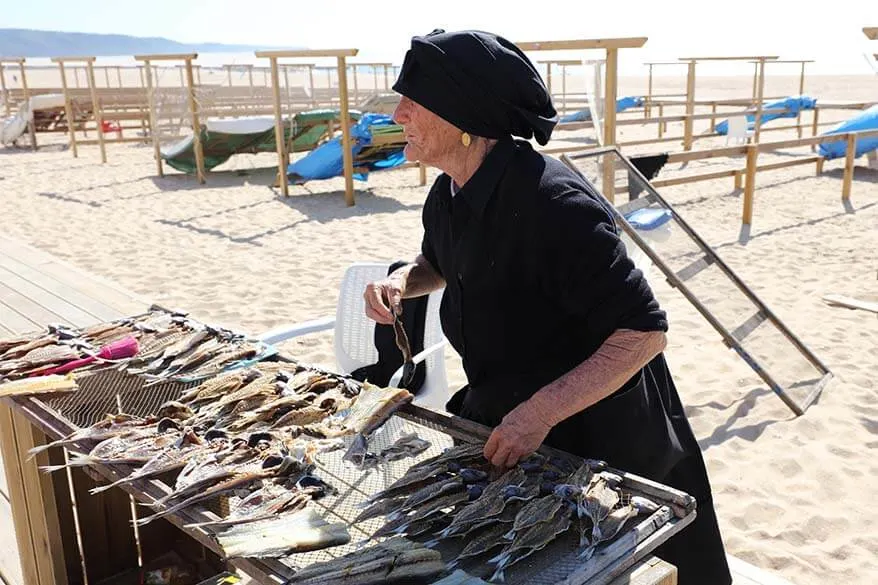Local women in traditional black clothing selling dried fish in Nazare Portugal