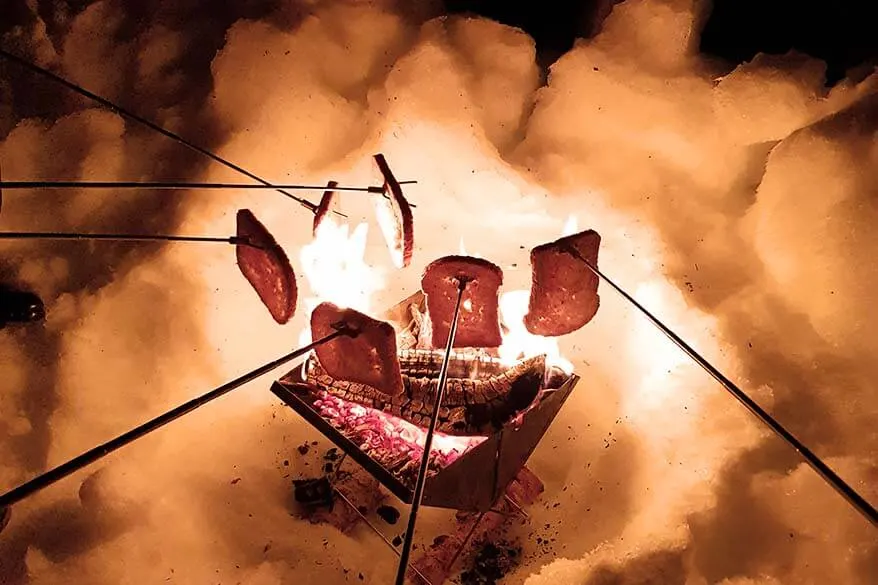 Toasting bread by the bonfire on a small group northern lights tour in Norway in winter