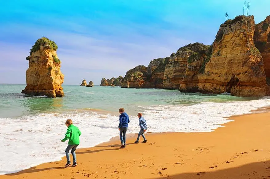 Kids playing on the beautiful Praia de Dona Ana beach near Lagos in Algarve, Portugal