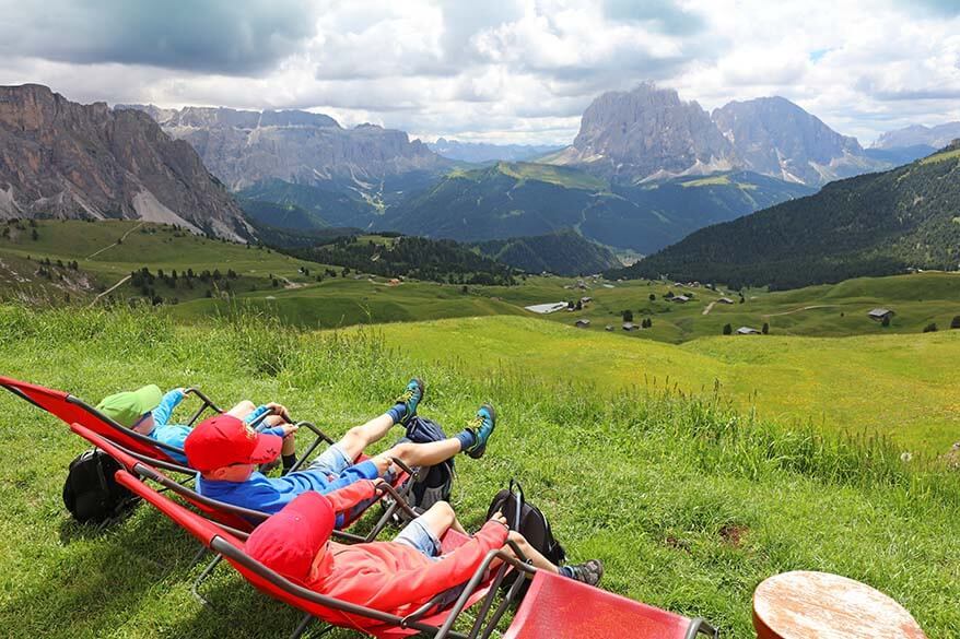 Kids relaxing after Seceda hike in the Dolomites on the terrace of Baita Troier mountain hut