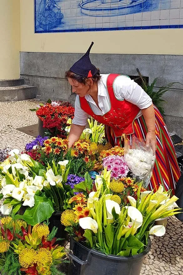 A woman in traditional Madeira folk clothing selling exotic flowers at Mercado dos Lavradores market in Funchal