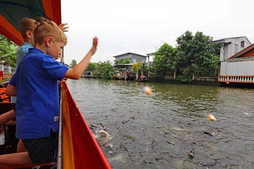 Kids feeding fish during Bangkok canal tour in Thonburi area