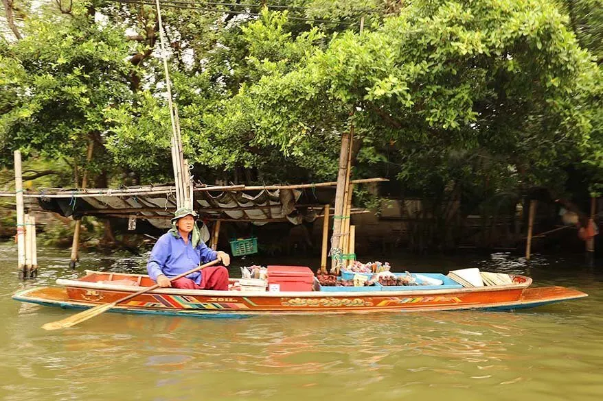 Vendor selling souvenirs from his wooden boat in Bangkok