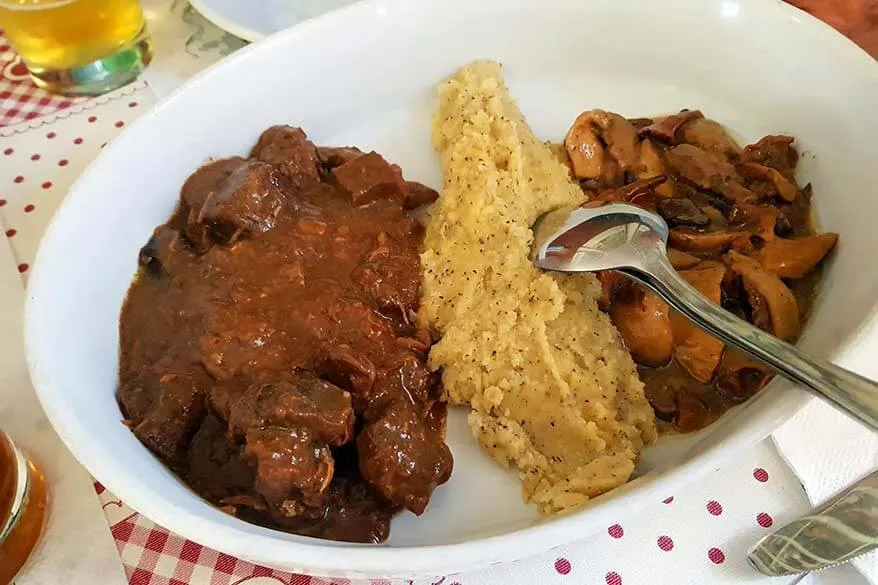 Polenta e cinghiale - polenta with a wild boar stew and mushrooms - traditional dish in Trentino region in Italy