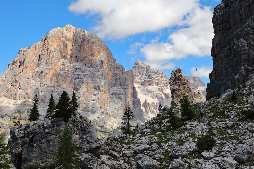 People climbing and walking a tightrope between the towers of Cinque Torri