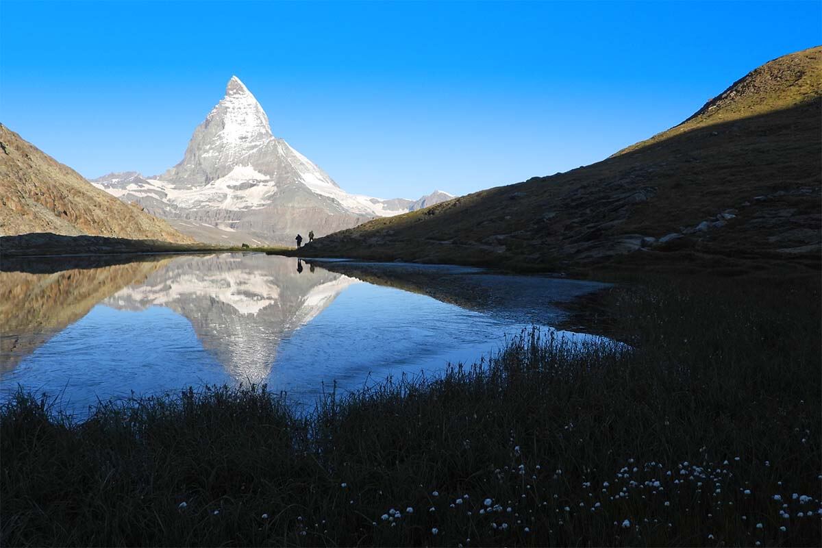 Hikers and Matterhorn reflections at Riffelsee Lake in Zermatt Switzerland