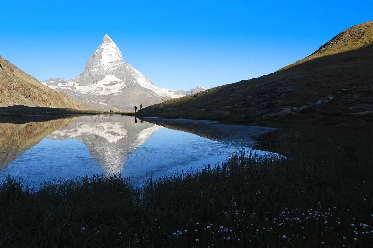 Hikers and Matterhorn reflections at Riffelsee Lake in Zermatt Switzerland