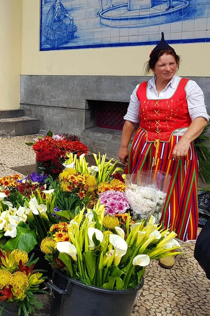 Woman in traditional clothing selling flowers at Mercado dos Lavradores in Funchal Madeira