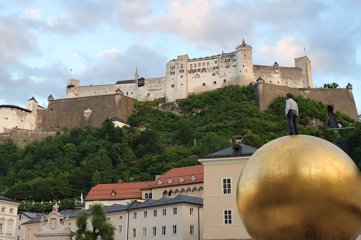Golden sphere on Kapitelplatz in Salzburg, with Hohensalzburg Fortress in the background.
