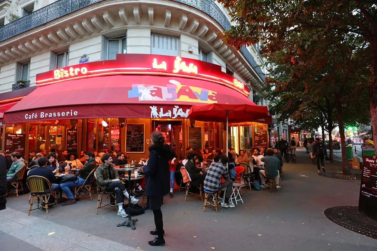 People sitting outside on the terrace of a traditional brasserie in Paris in October