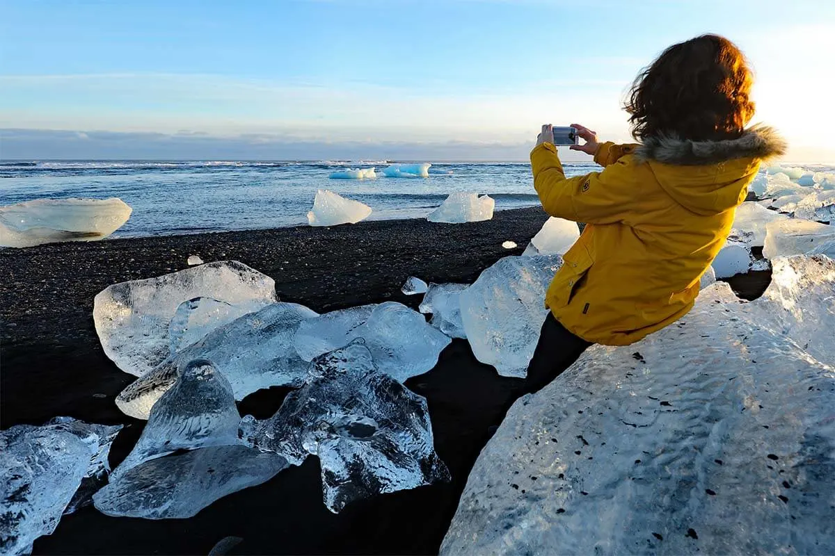 Woman taking pictures of the icebergs on the Diamond Beach in Iceland in winter