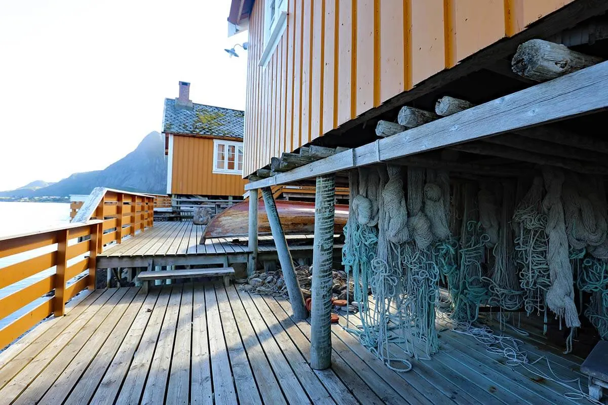Redes de pesca bajo cabañas rorbuer amarillas en Lofoten Noruega