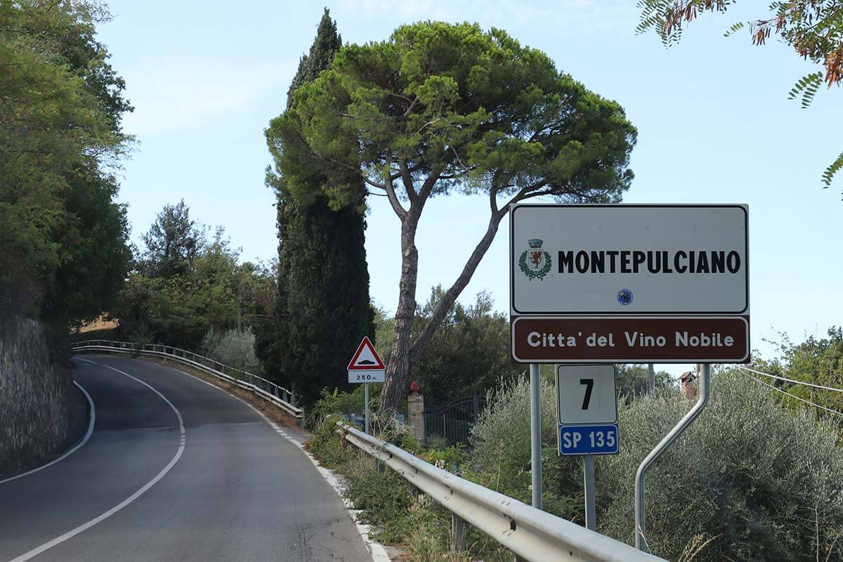Signo de la ciudad de Montepulciano al lado de la carretera en Toscana, Italia