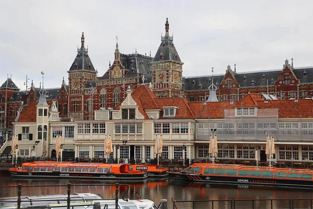 Amsterdam Central Station and canal cruise boats on a grey day in June