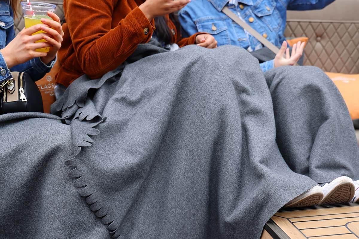 People wrapped in blankets on an open boat canal cruise in Amsterdam