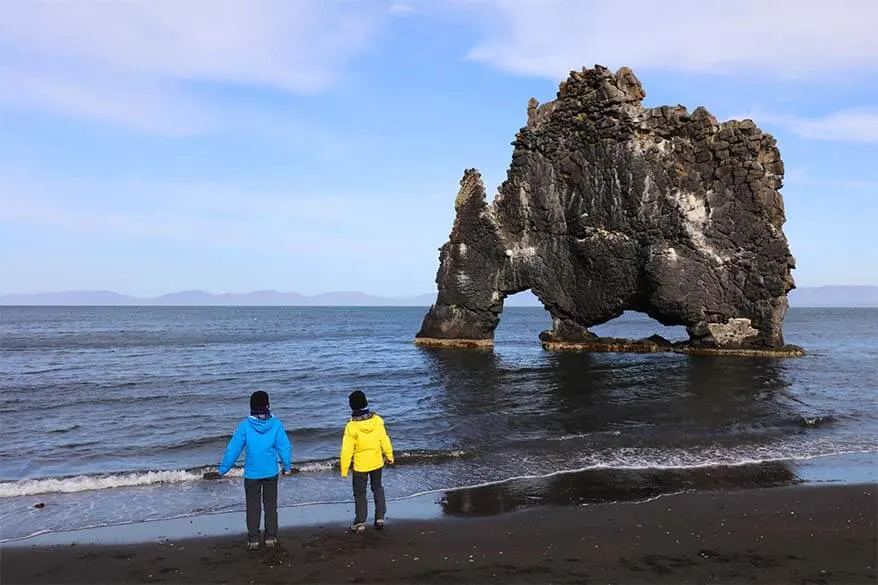 Kids wearing rain jackets and warm hats at Hvitserkur in Iceland in summer