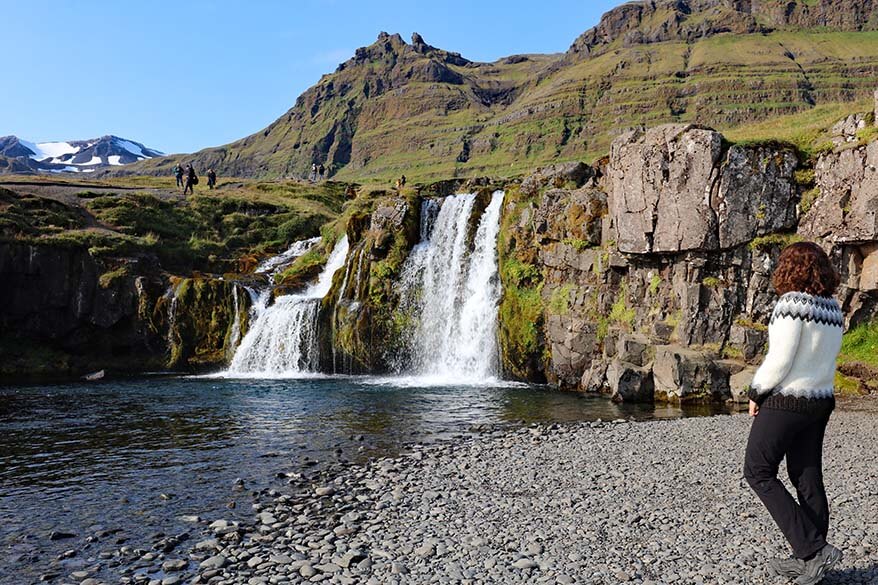Jurga at Kirkjufell waterfall in Iceland in summer wearing an Icelandic sweater