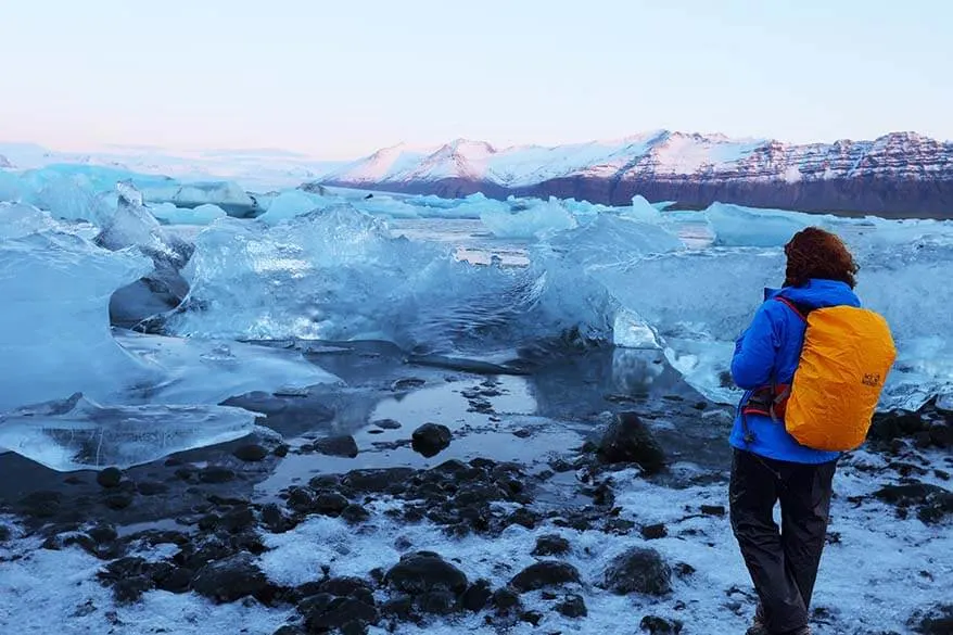 Woman wearing winter clothes and a backpack with waterproof rain cover in Iceland in winter