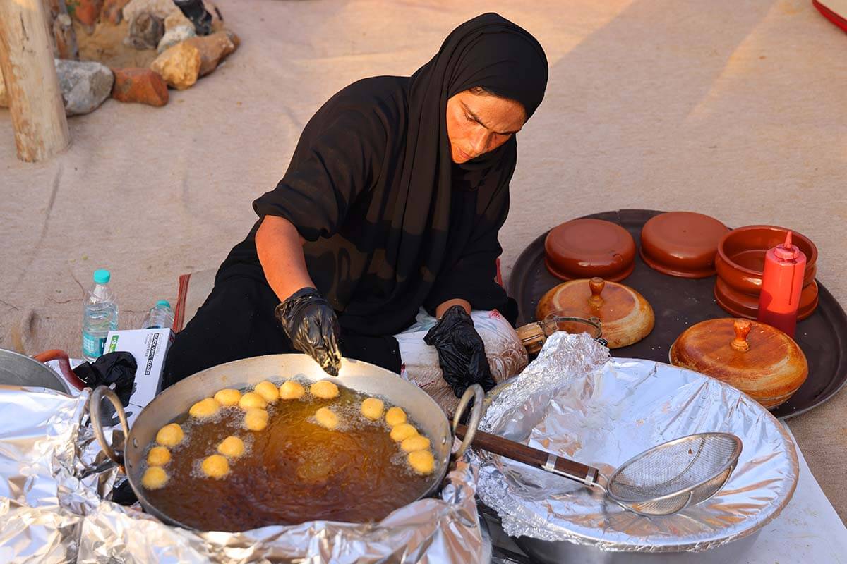 Emirati woman baking traditional luqaimat sweets in a desert camp in Dubai UAE