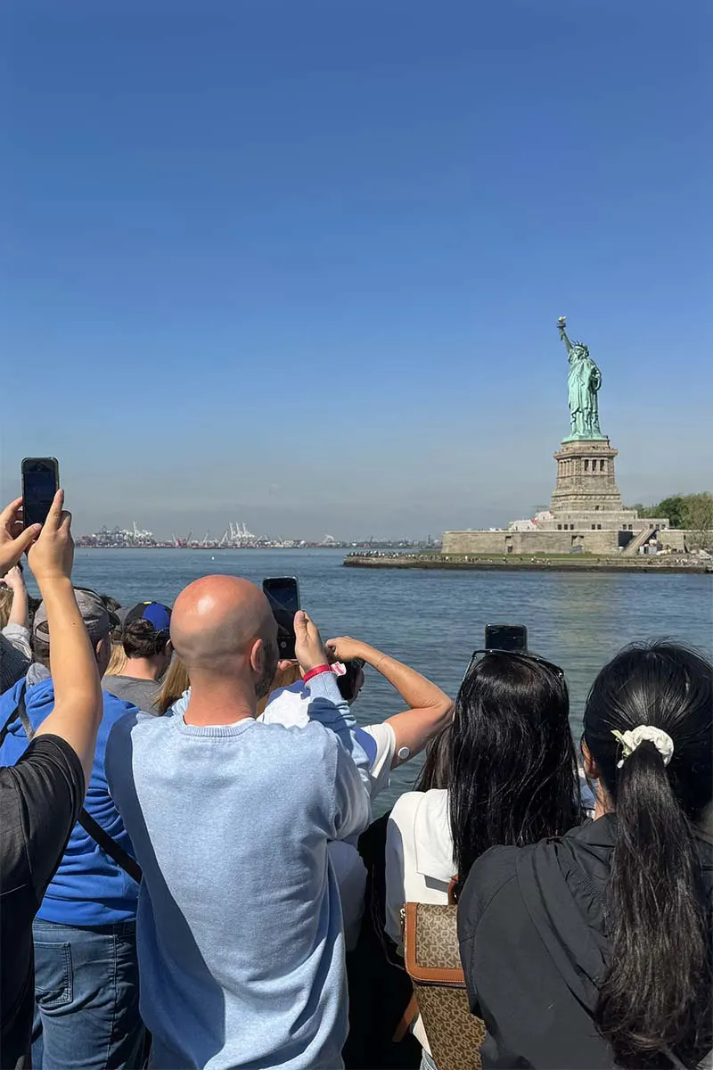 Tourists taking pictures of Liberty Statue on the ferry from New York