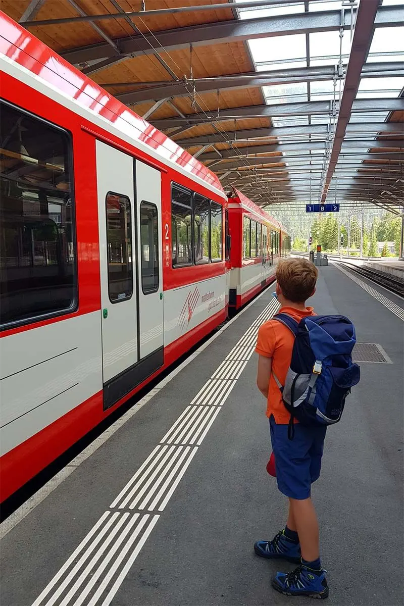 Boy waiting for a train in Zermatt Switzerland