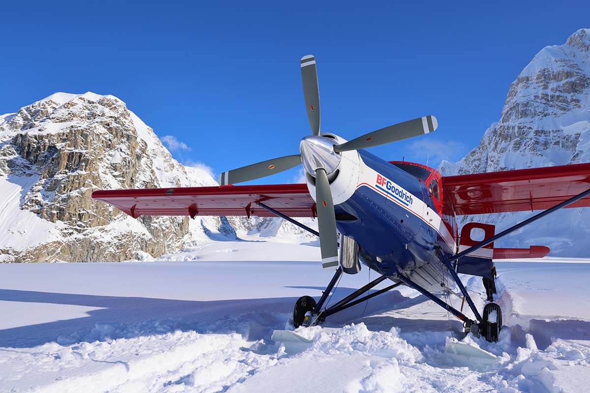 Denali glacier landing - airplane standing on the snow surrounded by mountains of Alaska range