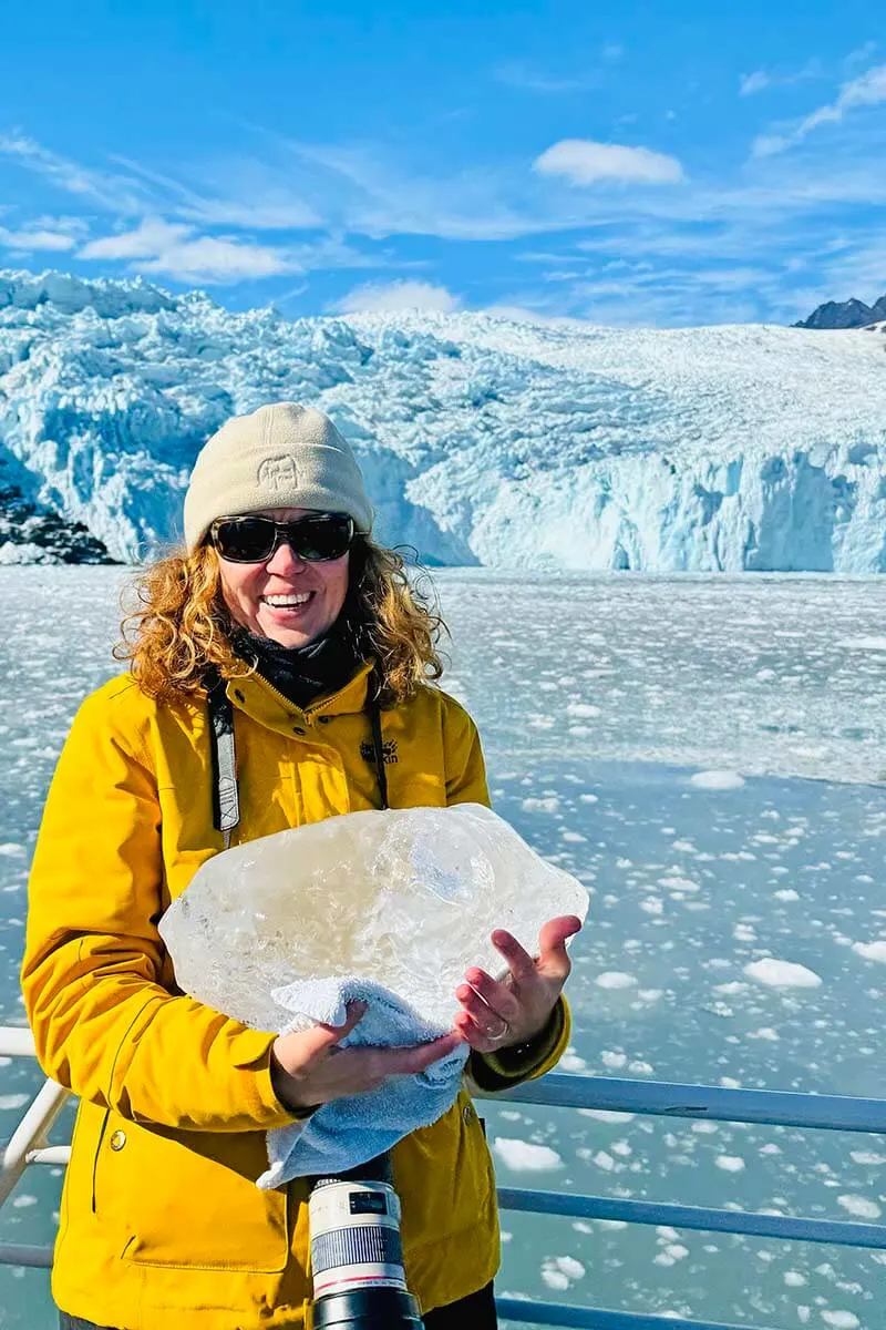 Jurga holding a big piece of ice in front of Aialik Glacier on Kenai Fjords cruise in Alaska