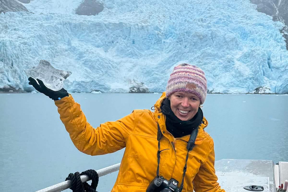 Jurga holding a piece of ice in front of a tidal glacier on Prince William Sound Cruise in Alaska