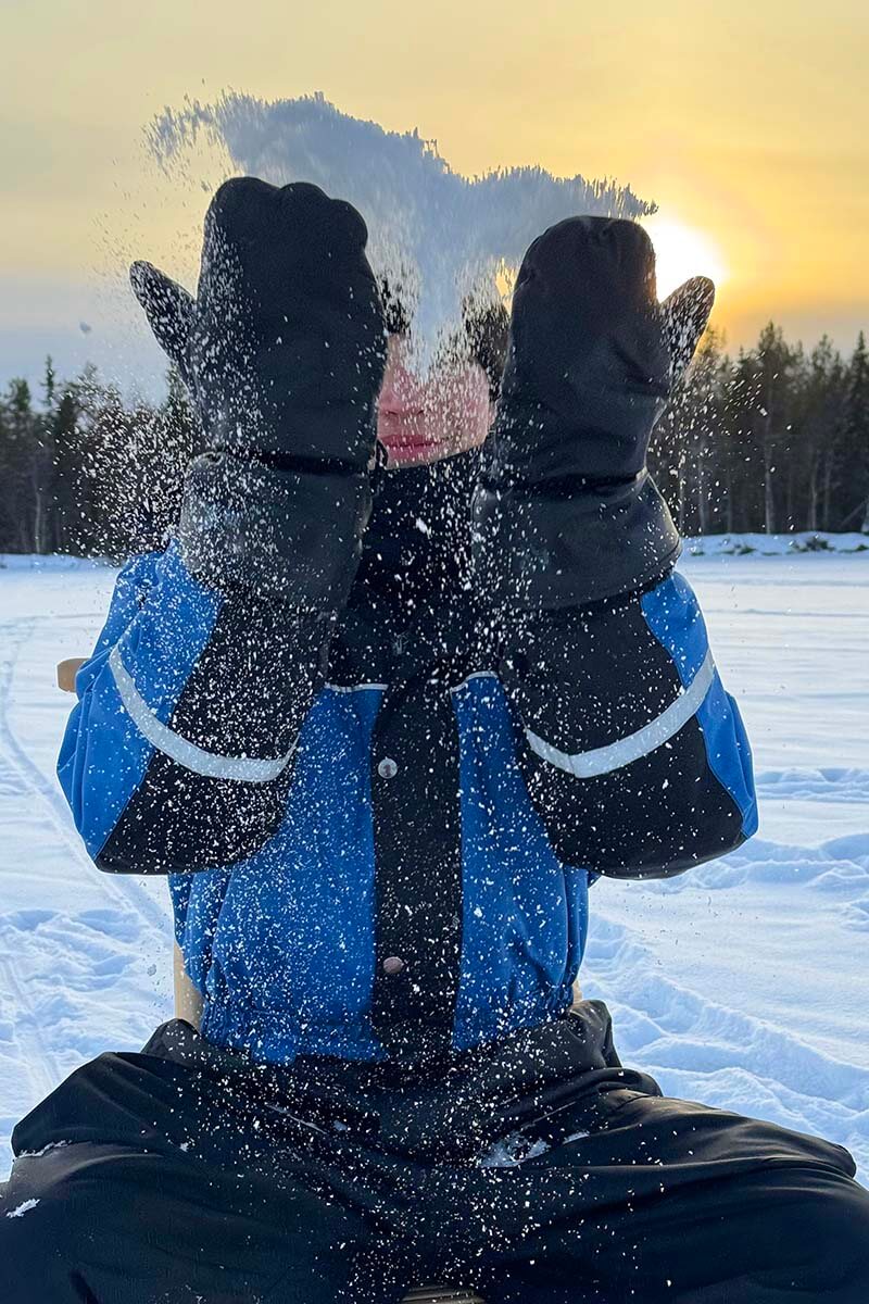 Boy playing in the snow dressed in full winter gear in Rovaniemi Lapland