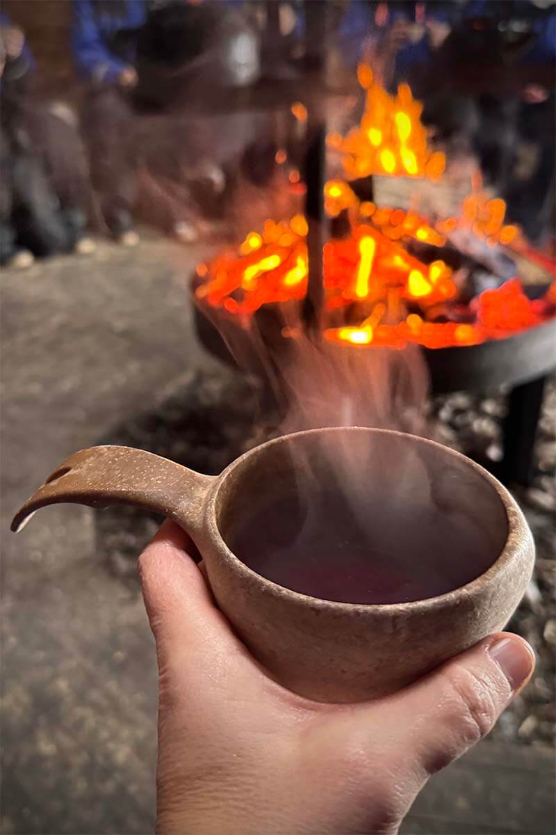 Lapland kota experience - drinking hot berry juice around the fire after a dog sled tour in Rovaniemi