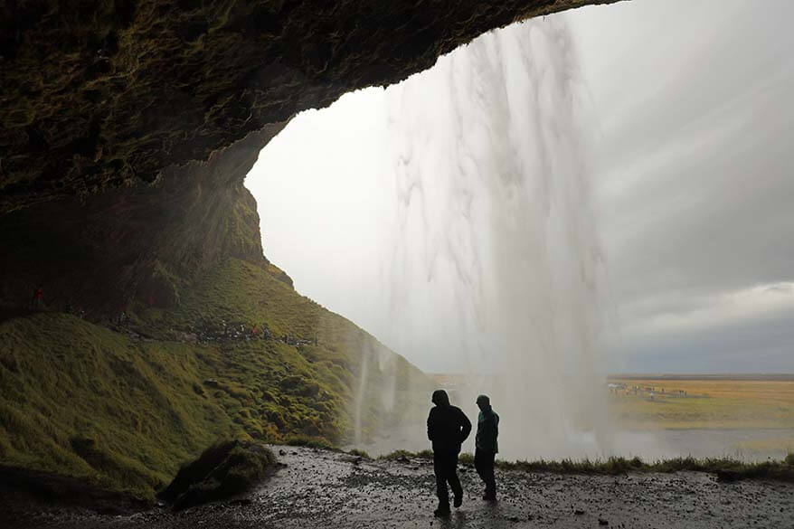 People in rainwear walking behind Seljalandsfoss Waterfall in Iceland