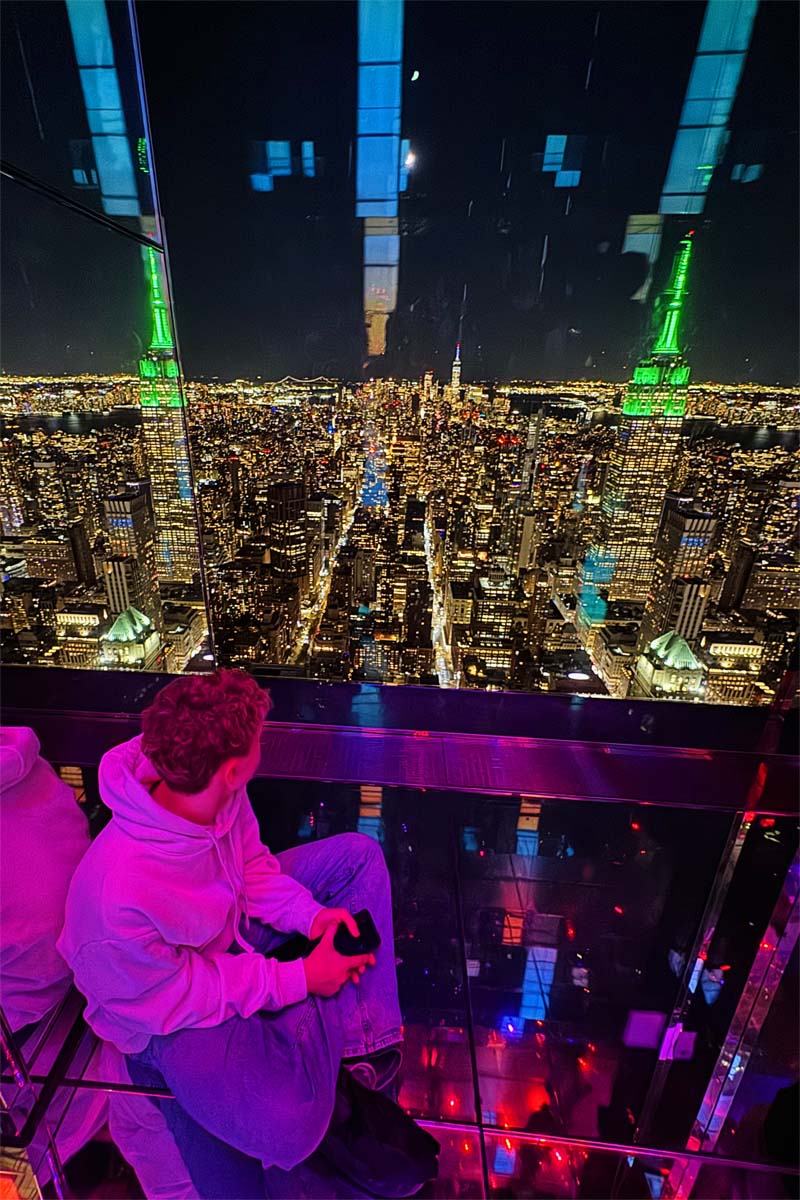 Teenager looking at Manhattan view at SUMMIT One Vanderbilt at night