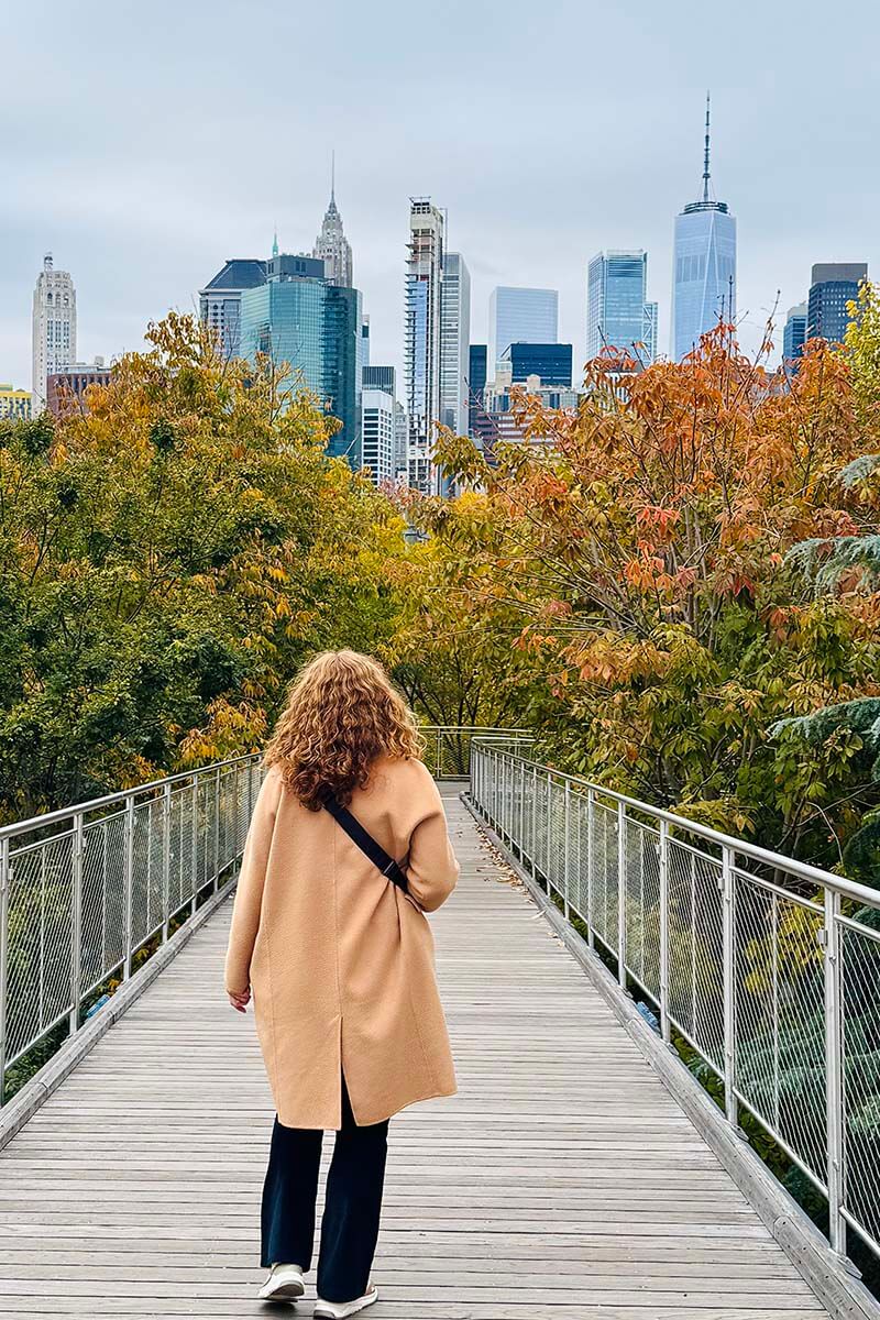 Woman in a coat walking on Squibb Park Bridge in Brooklyn New York in the fall