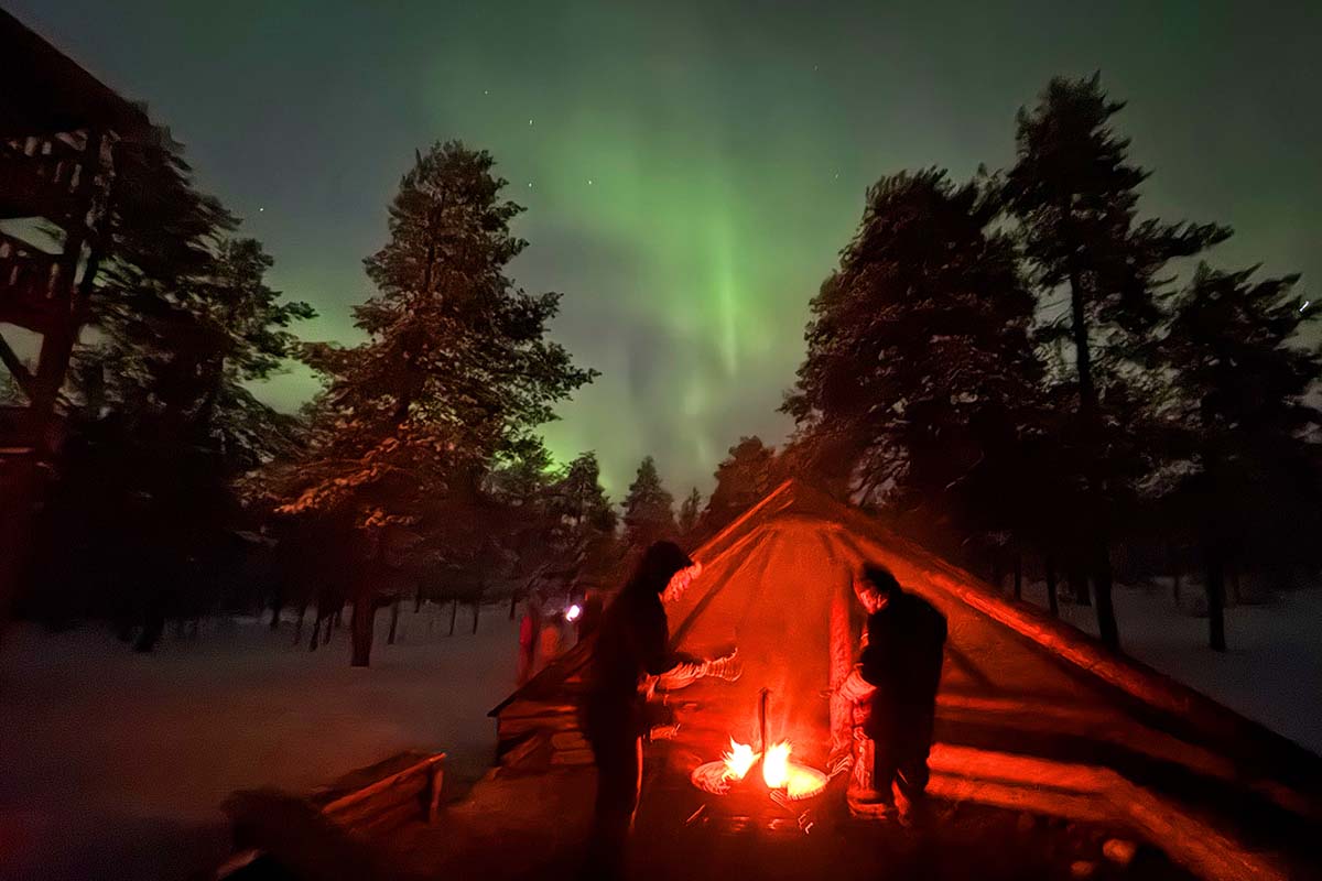 People watching Northern Lights and warming up by an outdoor fire in Ounasvaara Rovaniemi