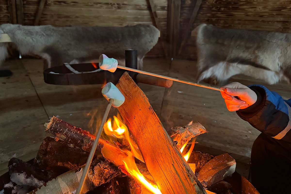 Roasting marshmallows in a traditional Finnish kota during our winter trip to Lapland