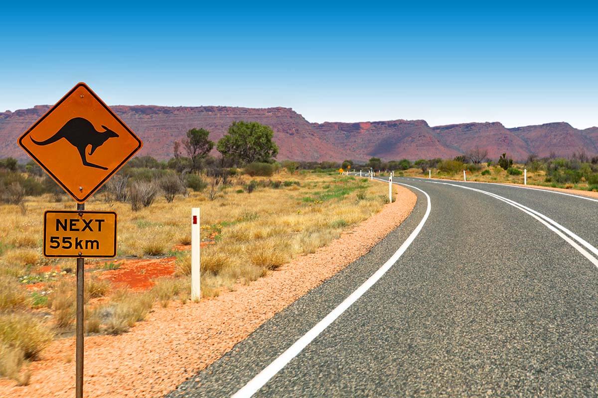 Empty road with kangaroo sign in outback Australia - top places for road trips in the world