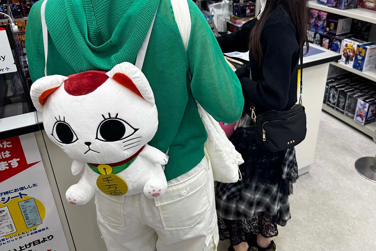Japanese love cute stuff - young woman with a cute cat-shaped backpack at an anime store in Tokyo