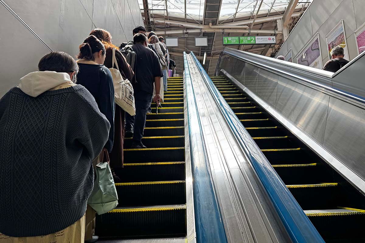 Japanese people politely standing in row on an escalator in a metro station