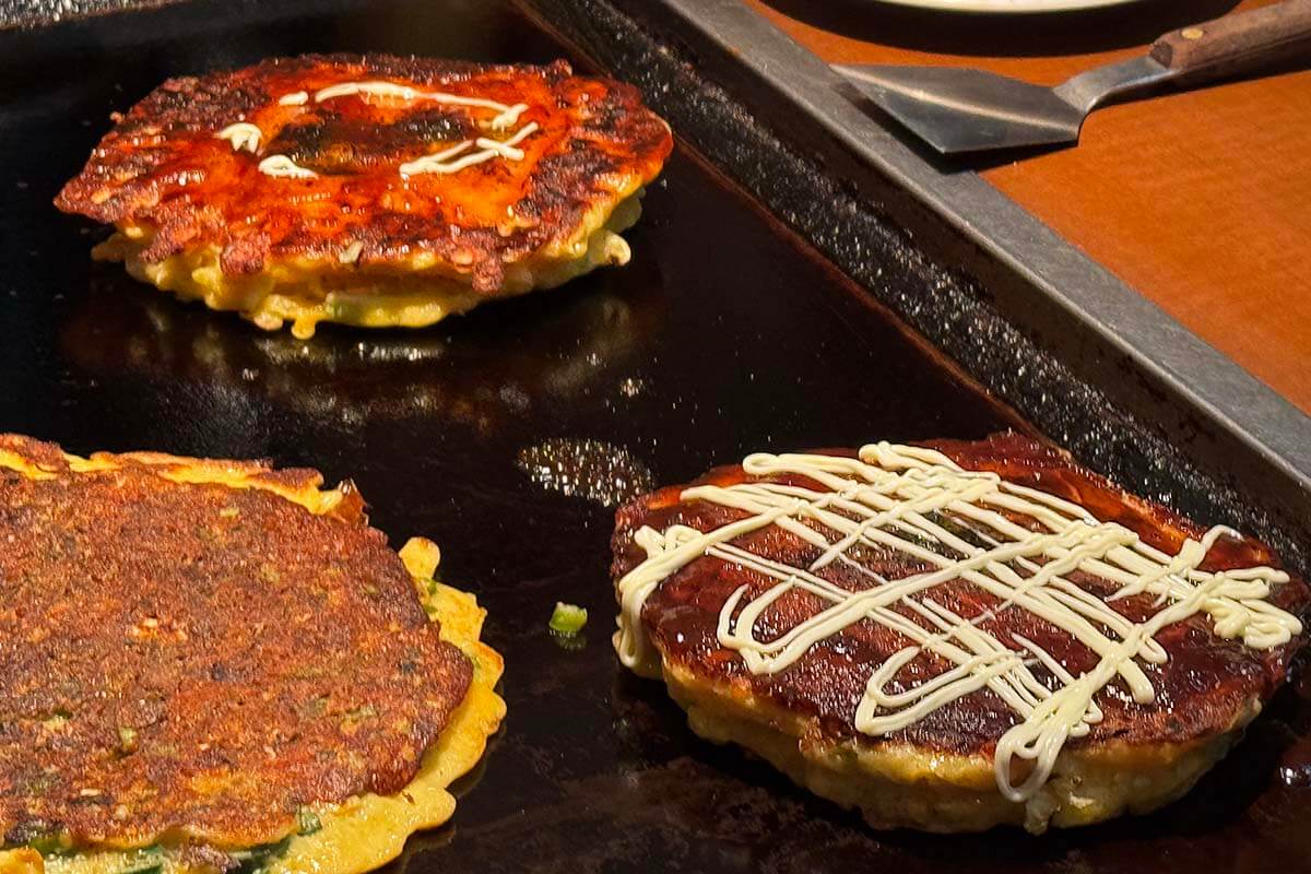Okonomiyaki savory pancakes on a hot grill at a local restaurant in Osaka