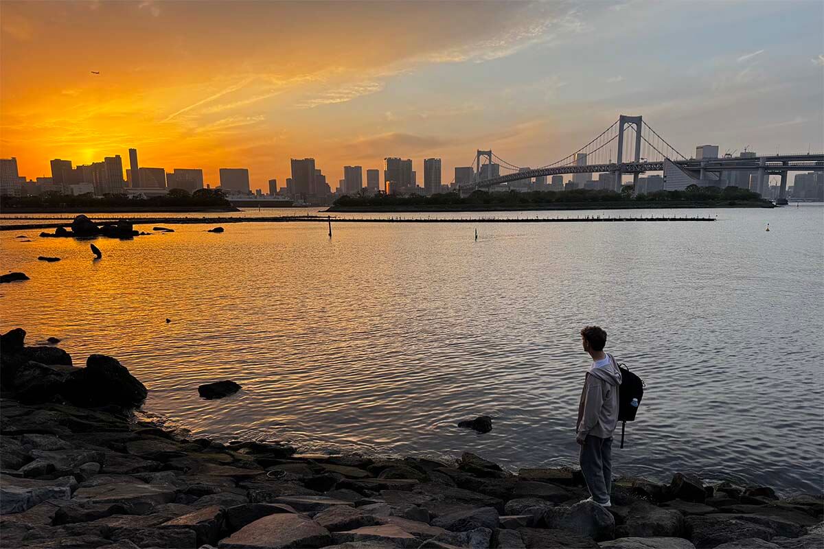 Teen enjoying sunset Odaiba Waterfront overlooking Tokyo Bay and Rainbow Bridge