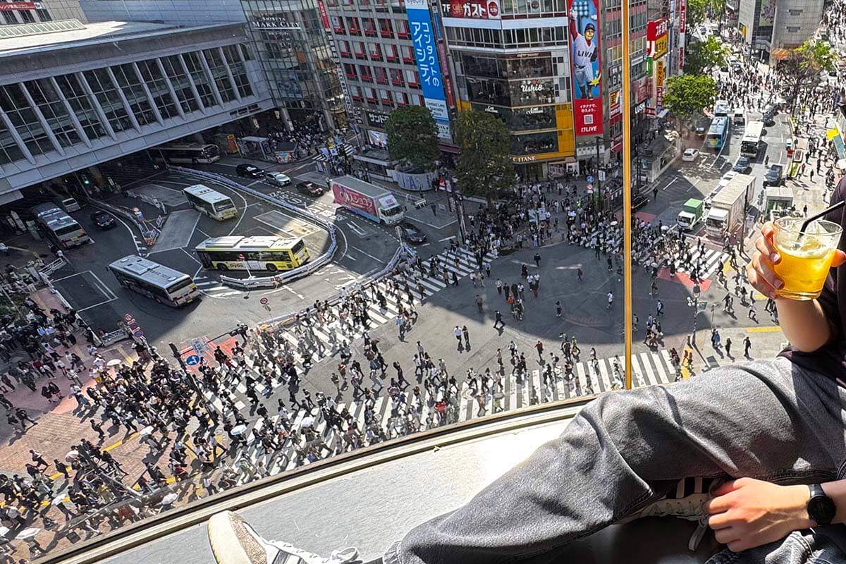 Teenager enjoying Shibuya Scramble view from a rooftop bar above the world’s busiest pedestrian crossing, Tokyo, Japan