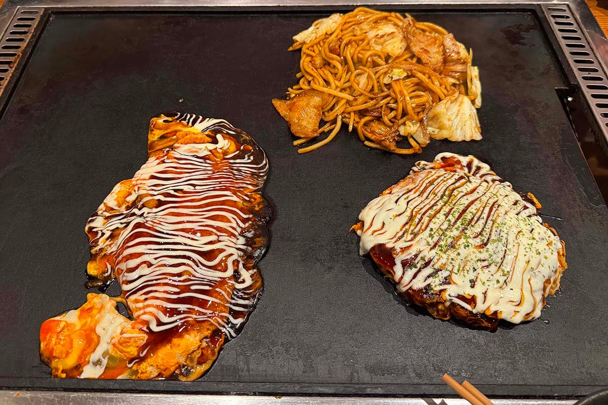 Tonpeiyaki, Okonomiyaki, and grilled noodles on a hot grill - Osaka food tour