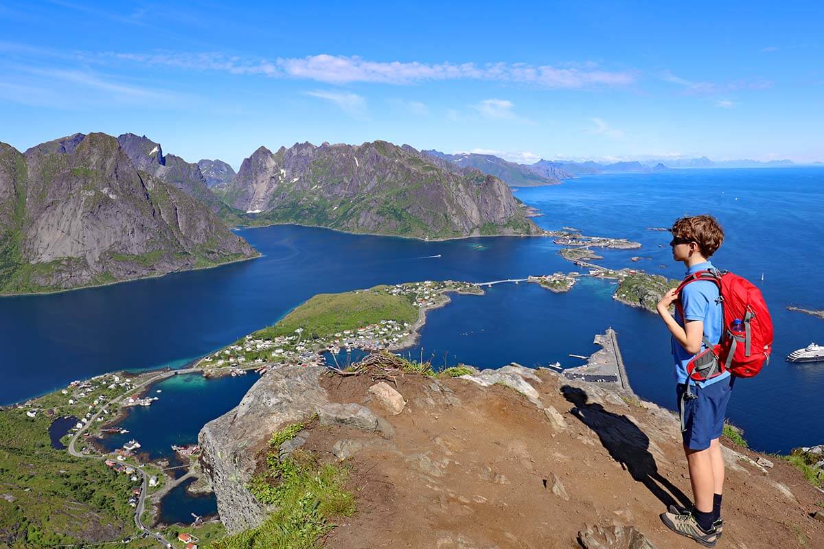 Hiker with a backpack at the Reinebringen viewpoint overlooking Reinefjord in Lofoten Islands, Norway