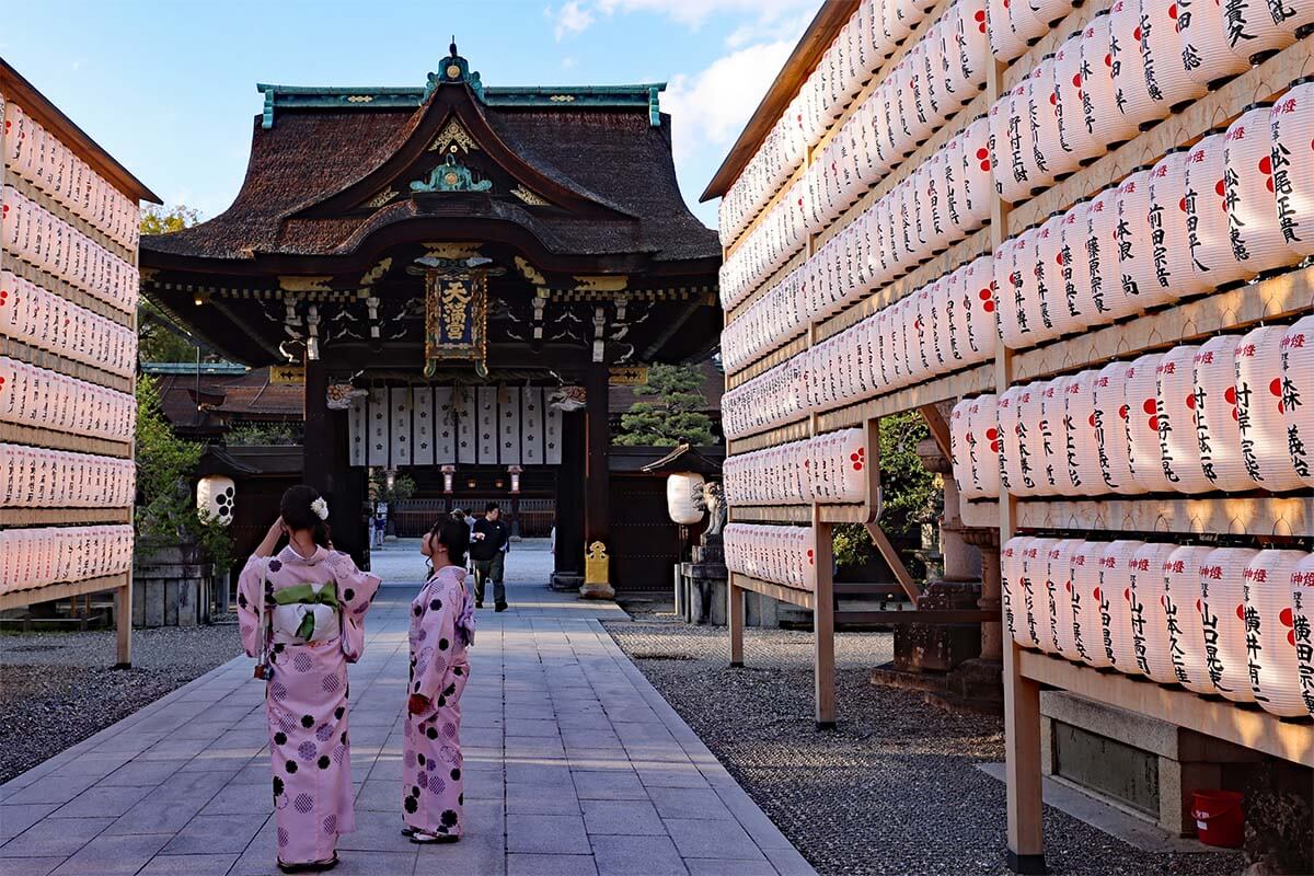 Lanterns and Japanese tourists in traditional clothing at Kitano Tenmangu shrine in Kyoto